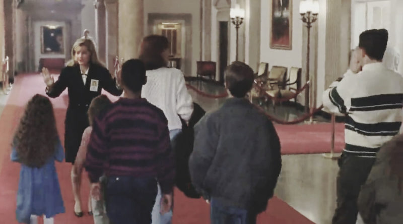 Screen grab of actress, Bonnie Hunt as a tour guide walking with a group through the White House.