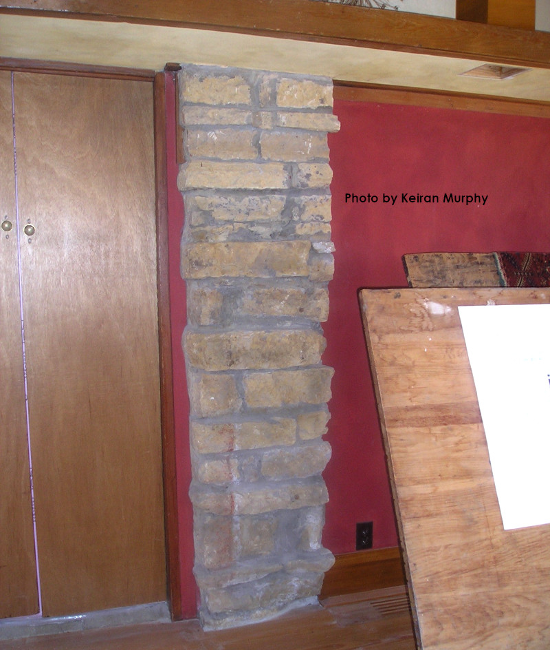 Photograph in Wright's studio looking at east wall, with a double door, a stone pier, and the red plaster wall.