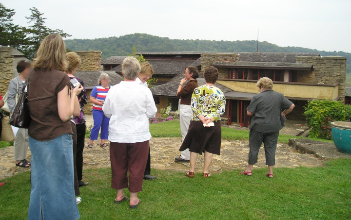 Photograph of Keiran with a tour group on Taliesin's Hill Crown. Keiran has white pants on.