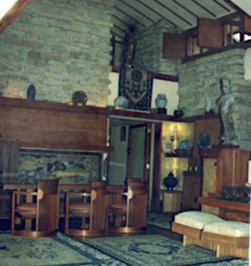 Interior of Taliesin Living room. In view: wooden furniture, limestone walls, and Asian artifacts. Photograph from 1992.