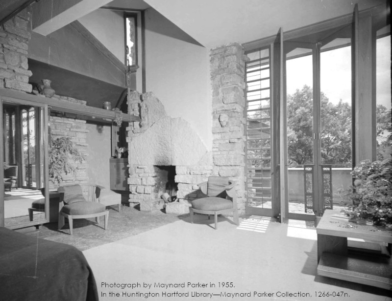 Photograph of Taliesin's Guest Bedroom taken by Maynard Parker in 1955. Has a bed, furniture, and a view out of the French doors. In Huntington Hartford Library--Maynard Parker collection, 1266-047n.